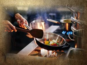 een persoon die voedsel kookt in een pan op een fornuis bij Burg-Hotel & Hostel Cochem in Cochem