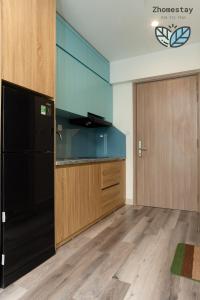une cuisine avec un réfrigérateur noir et des armoires en bois dans l'établissement Vinhomes Smartcity-Căn hộ dich vụ -Zhomestay, à Thượng Thôn