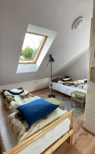 a attic bedroom with two beds and a window at Ozierański Raj "Pod rzeźbami" in Krynki