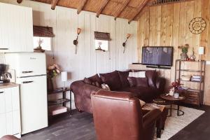 ein Wohnzimmer mit einem braunen Ledersofa und einem Kühlschrank in der Unterkunft The Barn - Aurora Hoeve - loft met jacuzzi in Oldekerk