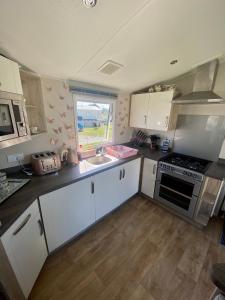 a kitchen with white cabinets and a stove and a window at Skye Breaks in Sheerness