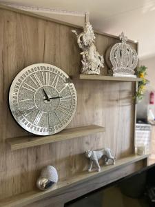 a clock on a wooden wall with two shelves at Skye Breaks in Sheerness