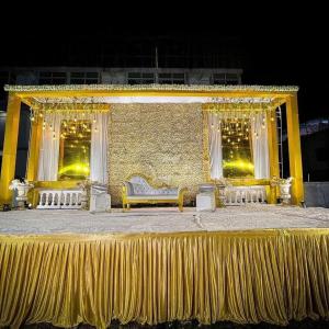 eine goldene Bühne mit Couch und Vorhängen darauf in der Unterkunft Hotel Emperor Paradise in Bilāspur