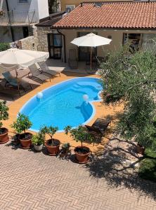 a swimming pool with chairs and umbrellas in a courtyard at B&B Villa Dall'Agnola in Garda