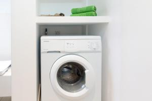 uma máquina de lavar e secar roupa branca num quarto branco em Ferienhaus Wattschnecke Norddeich em Norddeich