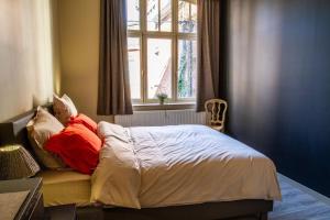 a bed with red pillows in a bedroom with a window at A l'ombre de la Croisette - Esc'Appart in Dinant