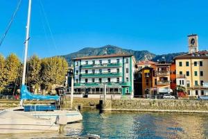 un gran edificio junto a un río con un barco en Casa vacanze Porto Valtravaglia Lago Maggiore en Porto Valtravaglia