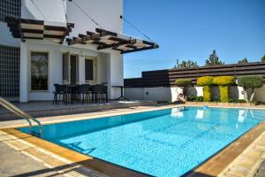 a swimming pool in front of a house at Ilios Villa in Larnaca