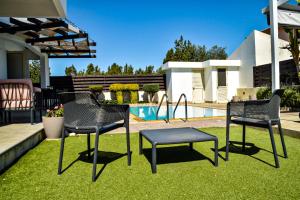 ラルナカにあるIlios Villaの椅子とテーブルのある庭、プール付
