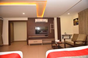 a hotel room with a couch and a tv at M R Residency Dharwad. in Dhārwād