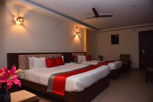 2 łóżka w pokoju hotelowym z czerwonymi poduszkami w obiekcie M R Residency Dharwad. w mieście Dharwad