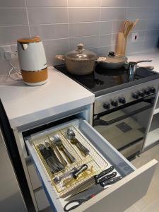 a kitchen with a stove and a drawer full of utensils at Modern Apartment in Racing Paradise: Close to Ferrari World & F1 Track in Abu Dhabi