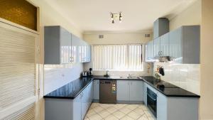 una cocina con armarios blancos y encimeras negras en Carlton 3 beds unit - free parking, en Sídney