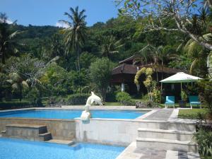 uma estátua de um golfinho sentado ao lado de uma piscina em Villa Campi Sorga em Senggigi