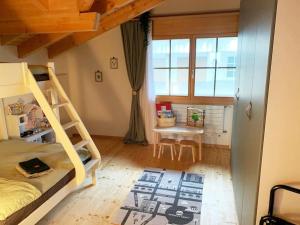 a bedroom with a bunk bed and a table and a window at Königin der Alpen in Beatenberg