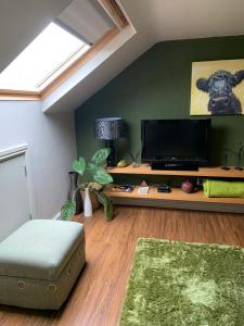a living room with a large tv and a green wall at First floor Pad Carterton near Burford in Shilton
