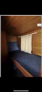 małe łóżko w pokoju z zasłoną w obiekcie Zouw Hausboat Zakotven -pouze ubytovaní w mieście Roudnice nad Labem