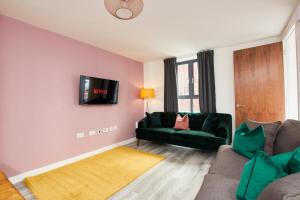 Beaut 5 Bed House w Parking في مانشستر: غرفة معيشة مع أريكة وتلفزيون على الحائط