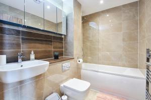 Beaut 5 Bed House w Parking في مانشستر: حمام مع حوض ومرحاض وحوض استحمام