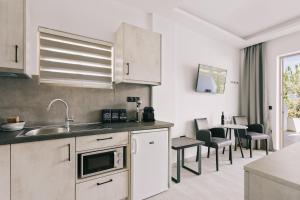 a kitchen with white cabinets and a table with chairs at Lighthouse Apartments in Stoupa