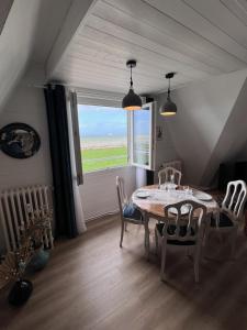 ein Esszimmer mit einem Tisch, Stühlen und einem Fenster in der Unterkunft L'air de la mer deux étoiles in Dieppe