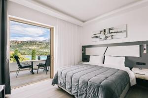 a bedroom with a bed and a balcony with a table at Lighthouse Apartments in Stoupa