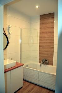 a white bathroom with a tub and a sink at Apartament mieszkanie dostęp zdalny bez potrzeby odbioru kluczy in Giżycko