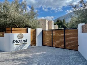 a wooden fence with a gate with a dogos sign on it at Diosas Luxury Villas in Pilaroú