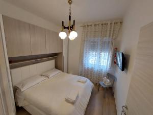 Habitación pequeña con cama blanca y lámpara de araña. en Da Enza, en Taranto