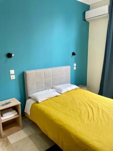 a blue bedroom with a bed with a yellow blanket at Hotel Kastoria in Thessaloniki