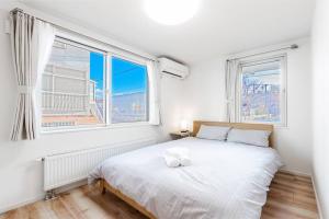 1 dormitorio con 1 cama blanca y 2 ventanas en GUEST HOUSE EARTH【THE MOON & THE SUN】, en Sapporo