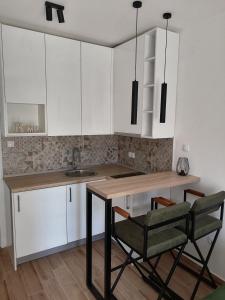 cocina con armarios blancos, mesa y sillas en WIN centar apartman, en Trebinje