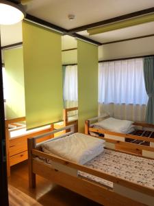 two beds in a room with green walls at Fukunae House in Takeda