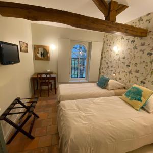 a bedroom with two beds and a table and a window at La Gironnerie in Loché-sur-Indrois