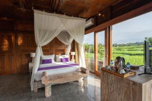 a bedroom with a bed and a large window at Uma Sebatu Villa in Tegalalang