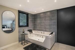 un ampio bagno con vasca e specchio di Relaxed Luxe "Boszichthuisje" met Jacuzzi Bospark Ijsselheide Hattemerbroek a Hattemerbroek Altre 42 foto