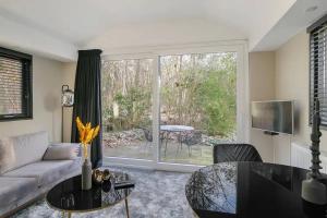 un soggiorno con un divano e un tavolo di Relaxed Luxe "Boszichthuisje" met Jacuzzi Bospark Ijsselheide Hattemerbroek a Hattemerbroek