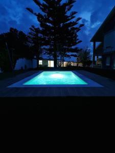 una piscina por la noche con un árbol en el fondo en CASA GORIS en Villanueva de Arosa
