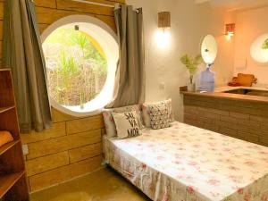 um pequeno quarto com uma cama e uma janela em Chalé Nova Terra em Imbassaí