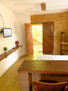 a room with a table and a door and a tv at Chalé Nova Terra in Imbassai