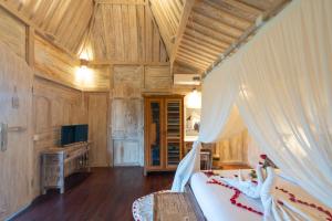 a bedroom with a bed and a tv in a room at Uma Sebatu Villa in Tegalalang