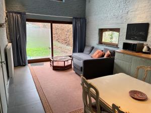 uma sala de estar com um sofá e uma mesa em Cosy little house em Kraainem