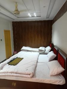 two twin beds in a room with at Mawa Hotel in Bālākot