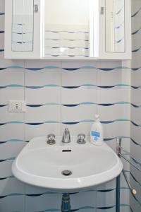 a white sink in a bathroom with blue and white tiles at Accomodo MIB25 Bivano Navigli in Milan