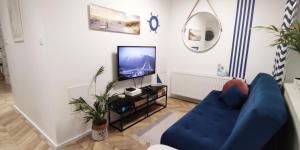 a living room with a blue couch and a tv at Kapitan Marina Gdynia Rental Apt in Gdynia