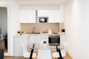 a kitchen with a glass table and white cabinets at Ring Inn Apartments in Obrenovac