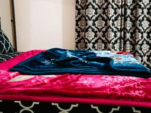 Una cama con una manta azul y roja. en Hotel Moon Light view, en Lahore