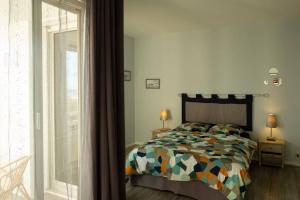 una camera da letto con un letto con un piumone colorato e una finestra di Beau F2, vue sur mer, à deux pas de Courseulles. a Bernières-sur-Mer