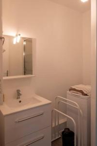 uma casa de banho branca com um lavatório e um espelho em Beau F2, vue sur mer, à deux pas de Courseulles. em Bernières-sur-Mer