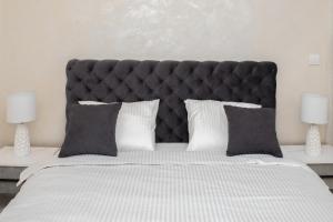 a large bed with a black headboard and two lamps at Ring Inn Apartments in Obrenovac